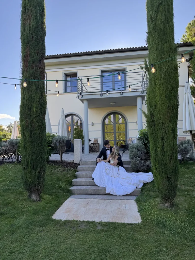 Brautpaar vor italienischer Villa mit Zypressen, elegante Hochzeit in der Toskana mit romantischer Gartenkulisse